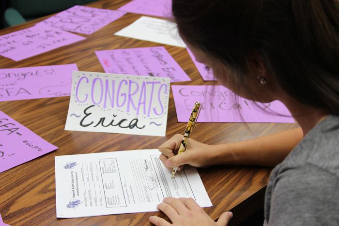 Amid purple and white congratulations cards from her teammates, Erica Lautensack, senior, signs to play golf at Stephen F. Austin University. She will join the collegiate team next fall.