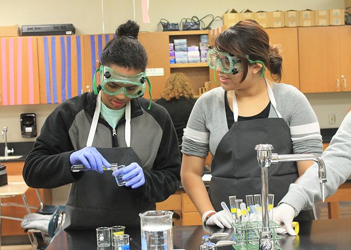 Junior Destiny Key pours iodine solution into her unknown chemical to determine what it is while junior Lee Cervantes watches.