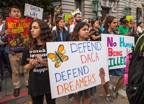 Protesters hold various signs and banners at a DACA rally in San Francisco. Image-Pax Ahimsa Gethen/Creative Commons